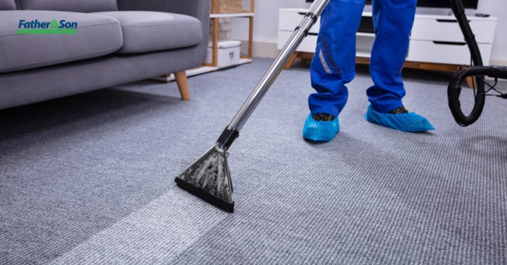 Wearing blue protective shoe covers, an individual meticulously cleans a gray carpet with a vacuum cleaner. Discover affordable commercial carpet cleaning solutions in Utah for pristine results every time.